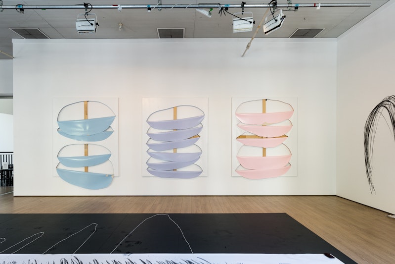 Three canvases painted with three different pastel colours, cut in circles and peeled back, hung on a white gallery wall