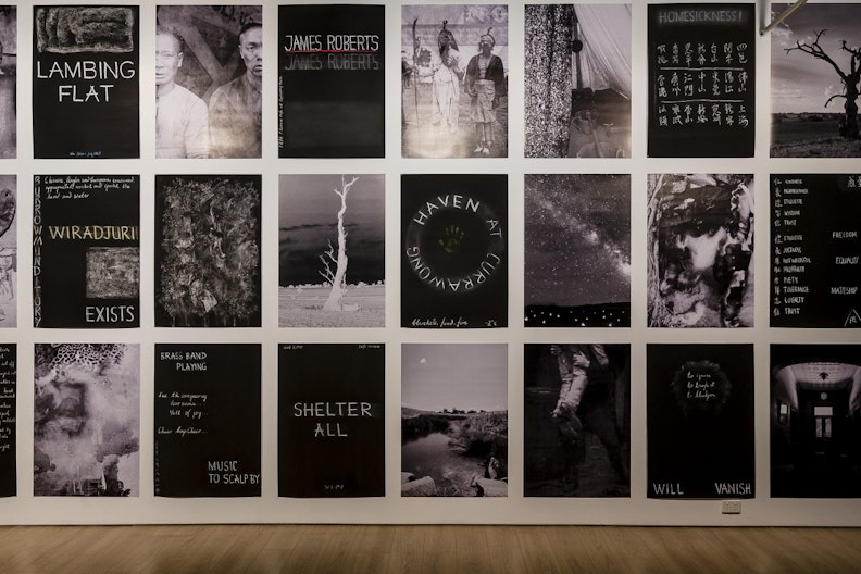 A series of 27 black and white posters showing barren trees in the Australian outback, a photograph of the Milky Way and figures of East Asian appearance. Some of the posters are printed with handwritten words such as 'Lambing Flat', 'James Roberts' 'Wiradjuri Exists', 'Haven at Currawong', 'Shelter All' and 'Homesickness'. Some posters are printed with handwritten Chinese characters.