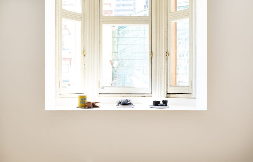 A naturally lit window sill with three groups of plates stacked in the sun.