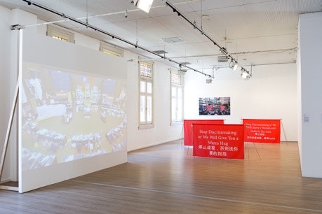 A video is projected onto a white floor screen. Next to it are three red banners placed on the ground in other, with the slogans in both English and Chinese written in white colour.