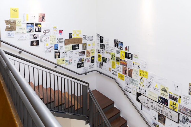 A real and reproduced protest posters from The Hong Kong Umbrella Movement are pasted on the wall along the staircase.