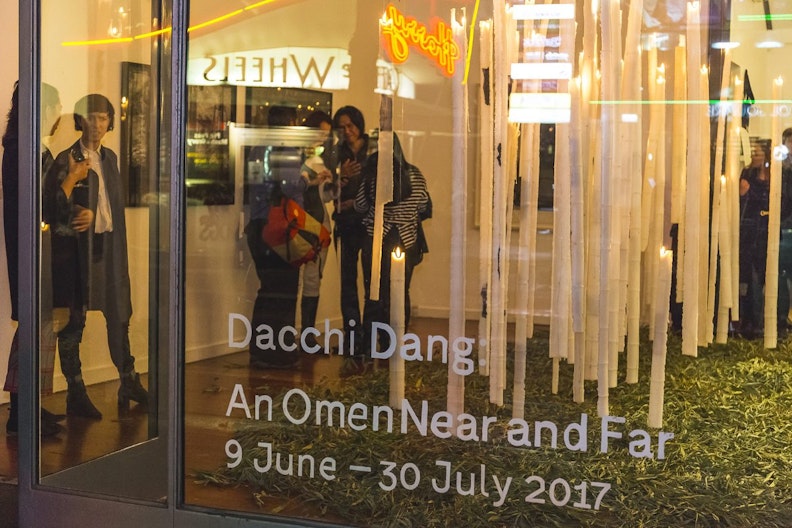 The gallery viewed through the exterior glass window. The text on the window reads 'Dacchi Dang, An Omen Near and Far, 9 June - 30 July 2017'