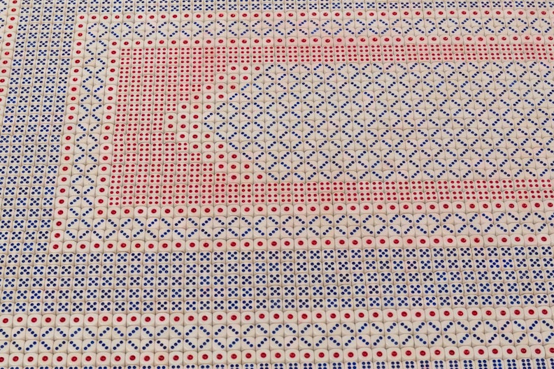 A close-up of a prayer mat showing intricate its geometric patterns. made of hundreds of playing die