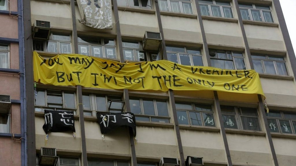 A yellow banner that reads 'You may say I'm a dreamer but I'm not the only one' on an apartment block complex.