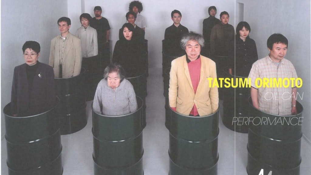 A group of people standing in black oil cans as part of Tatsumi Orimoto's Oil Can performance