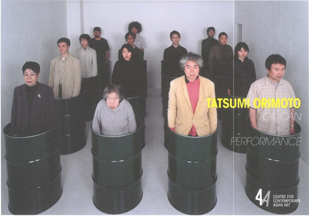 A group of people standing in black oil cans as part of Tatsumi Orimoto's Oil Can performance