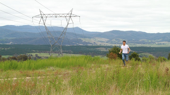 A photo of a person running in an open grassy area with hills in the distance