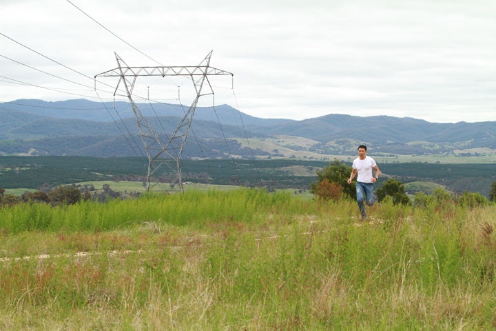 A photo of a person running in an open grassy area with hills in the distance