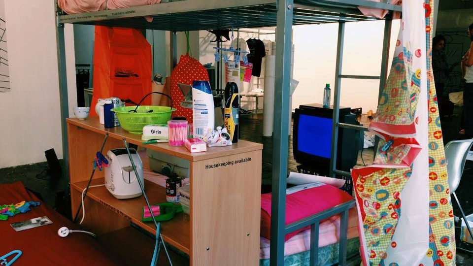 A photo from the Vertical Villages exhibition, showing a bunk bed, bedside table, and TV monitor