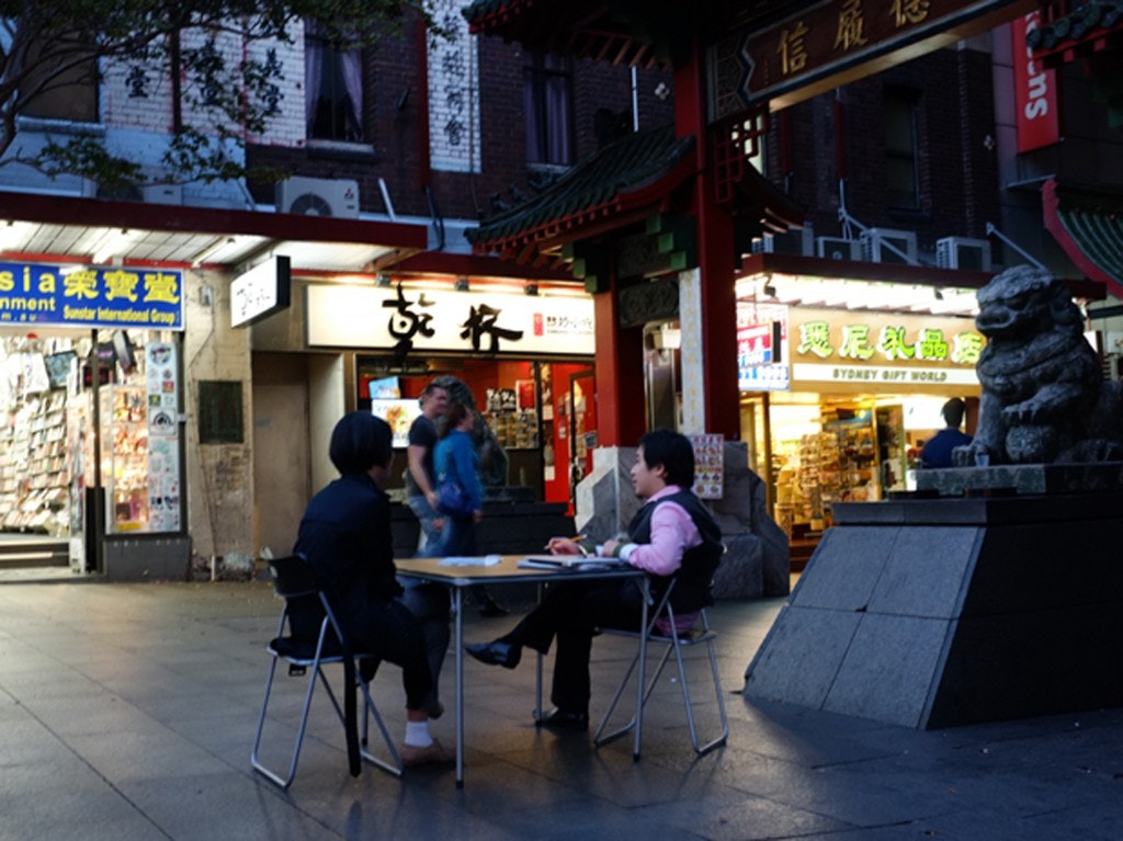 A photo of two people sitting at a table at the entrance to Dixon Street Mall