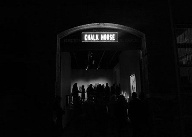 A dark photograph showing people gathering at the contemporary art space Chalk Horse