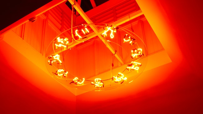 A neon light installation lighting up a ceiling in orange and red