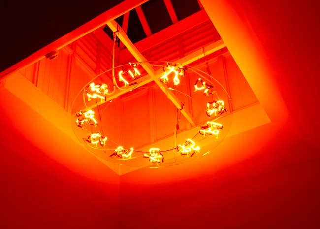 A neon light installation lighting up a ceiling in orange and red