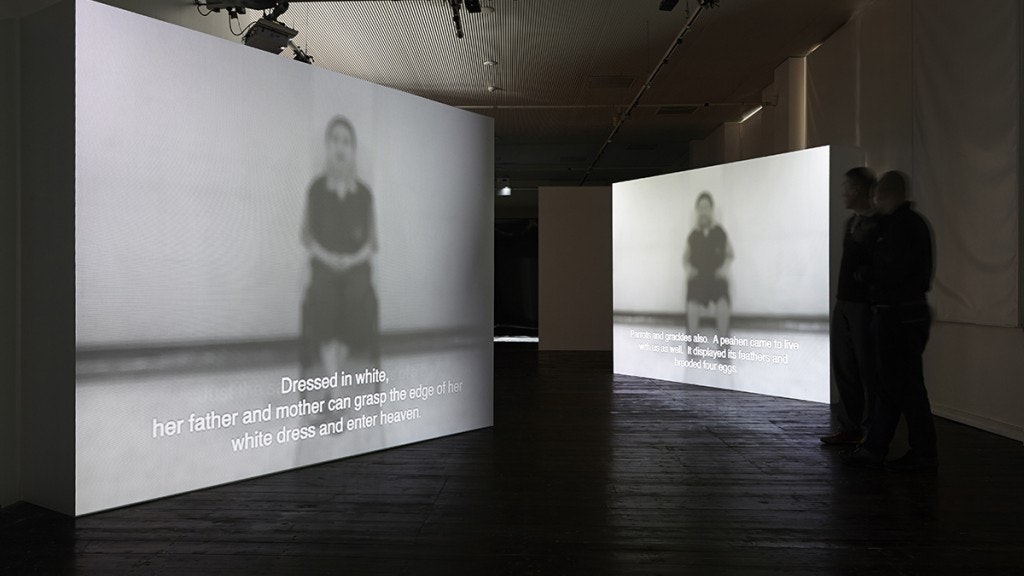 A photo depicting Araya Rasdjarmrearnsook, Great Times Message, Storyteller of the Town, The Insane (2006), three-channel video installation, installation view, at 4A