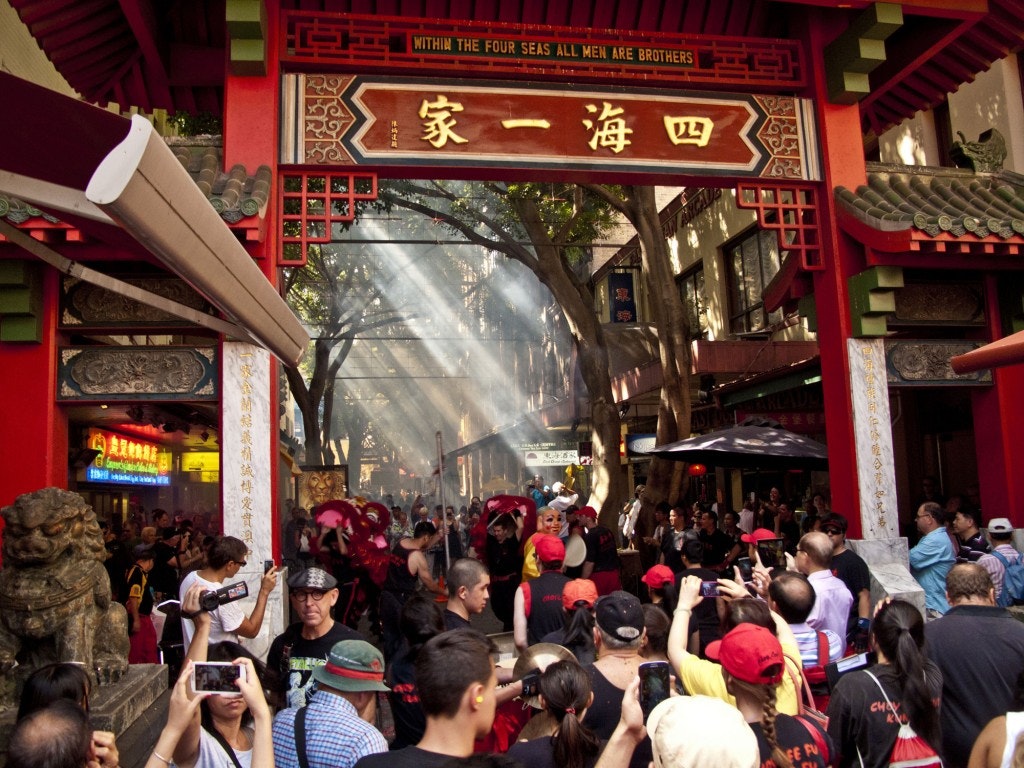 A photo of Dixon Street Mall, a large crowd takes photos of and watches a performance