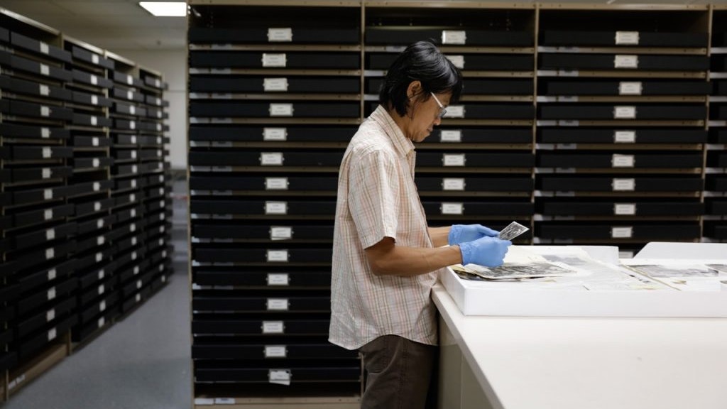A photo of Dacchi Dang examining documents in an archive