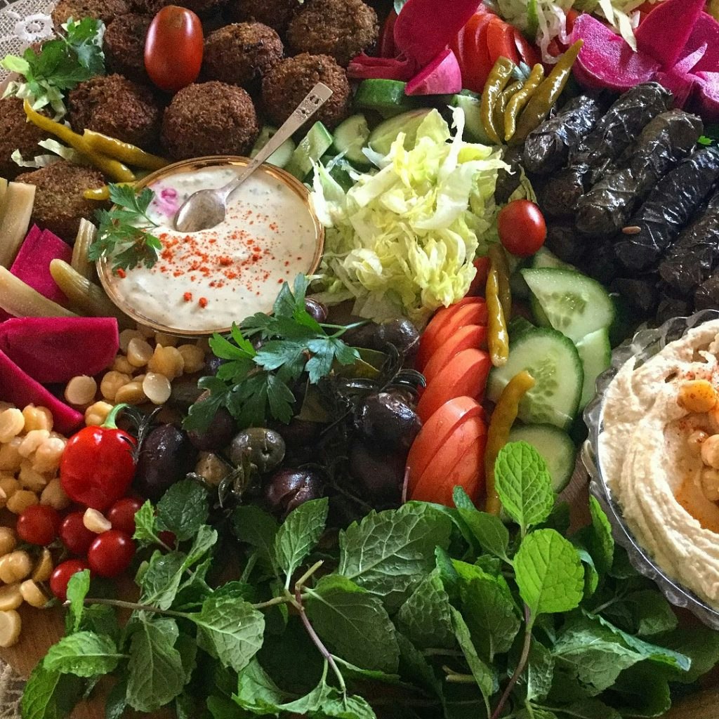 A photo of Lebanese food, including colourful vegetables, falafel, and hummus.