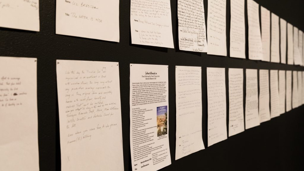 A4 sheets on paper covered in writing pinned on a black wall.