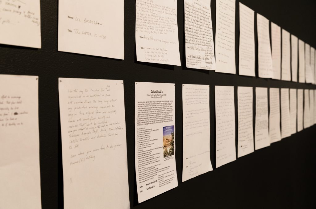 A4 sheets on paper covered in writing pinned on a black wall.