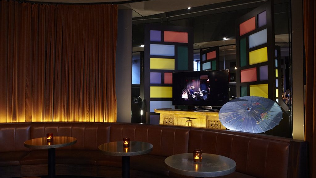 Inside Golden Age Cinema and Bar, tables, booths, golden curtains, and a TV monitor