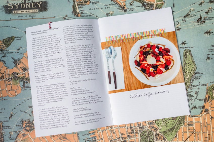 An opened zine showing text and a photo of a meal, laid ontop of a map of Sydney.