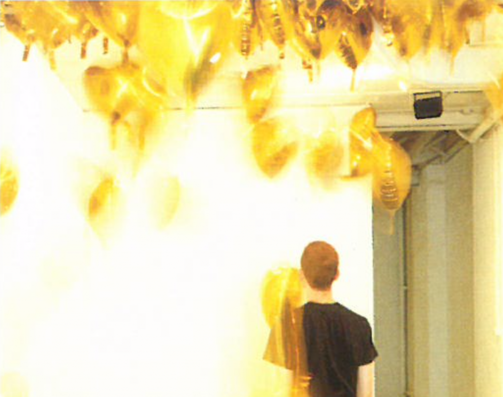 The back of a person and gold-coloured balloons lining the ceiling.