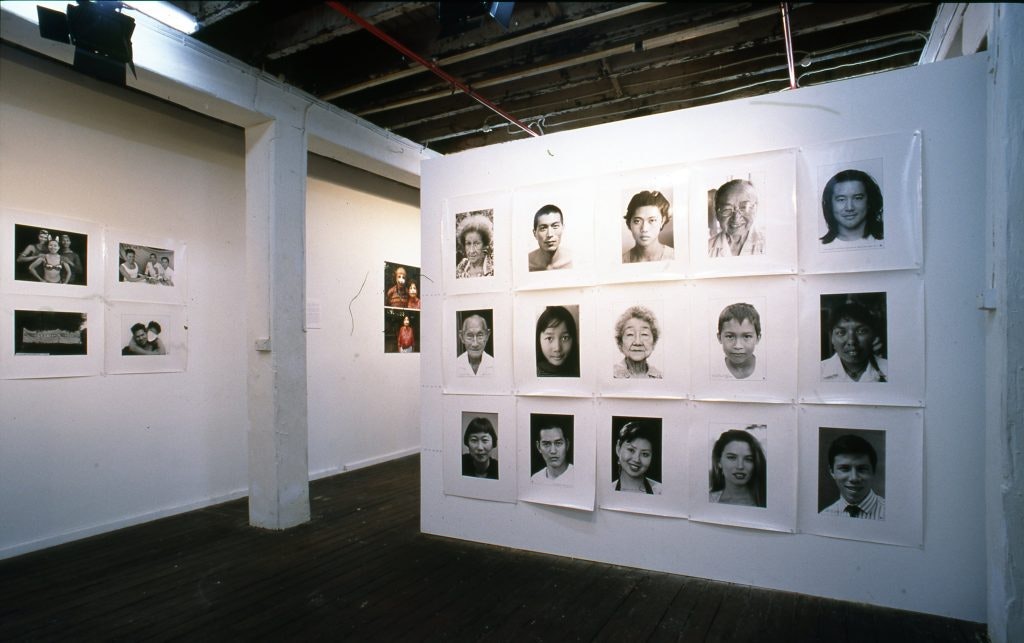 Black and white portrait headshots displayed on white gallery walls.