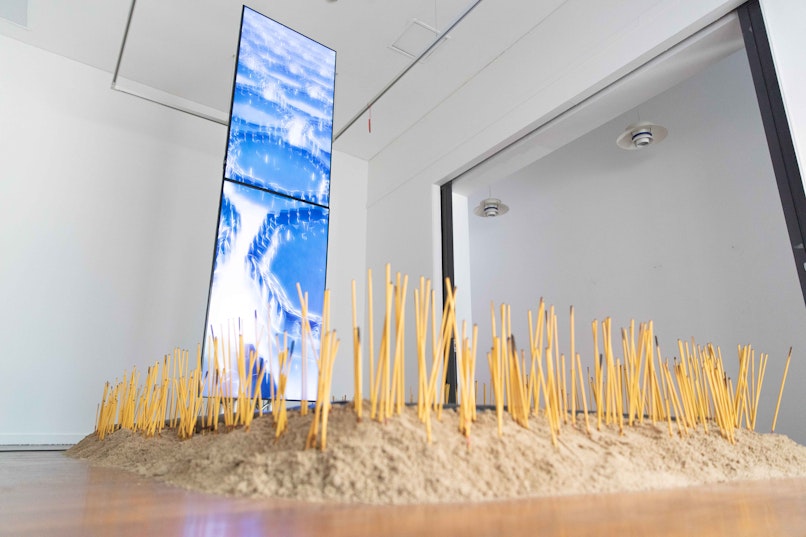 Rel Pham, Cache, 2023, incense, sand, talismans, trinkets, two-channel video, 4m 0s and water, dimensions variable. Commissioned by 4A Centre for Contemporary Asian Art. Supported by The City of Sydney’s Lunar New Year 2023, Festivals and Events Sponsorship Grant Program. Image: Anna Hay