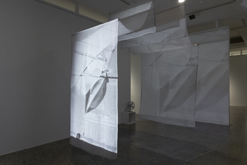 Allison Chhorn, Disintegrate/Regenerate (‘Memory House’ Revisited), 2025, single-channel video, 12 min, 35mm black and white photographs, sheer linen. Produced by Chris Luscri. Courtesy of the artist.