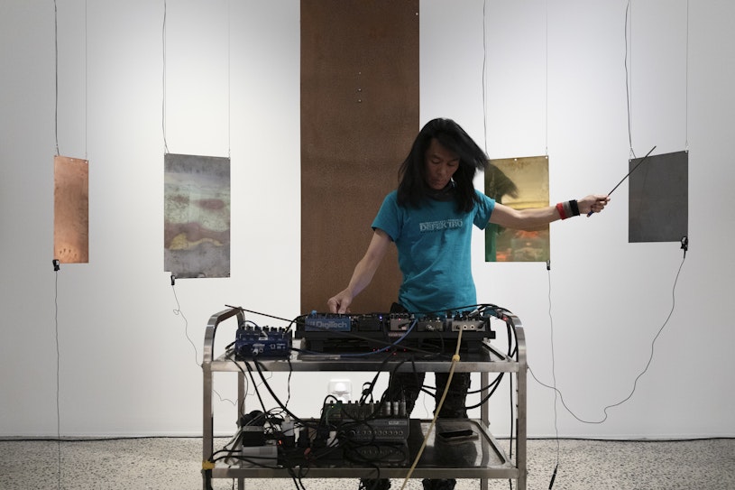 Hirofumi Uchino (aka. Defektro), The Taste of Poisons 3 (performance documentation), 2025, metal sheets (iron, brass, copper, aluminum, titanium, tungsten, indium) and vibration speakers with sound. Courtesy of the artist.