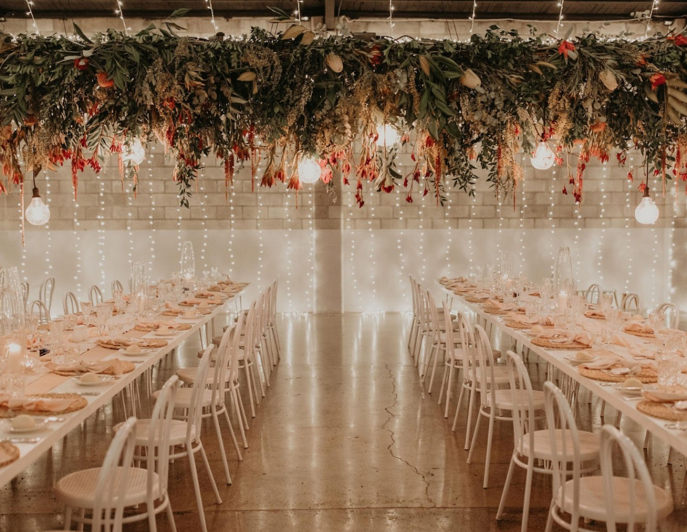 Floral and lighting installation set over tables styled for a wedding reception.