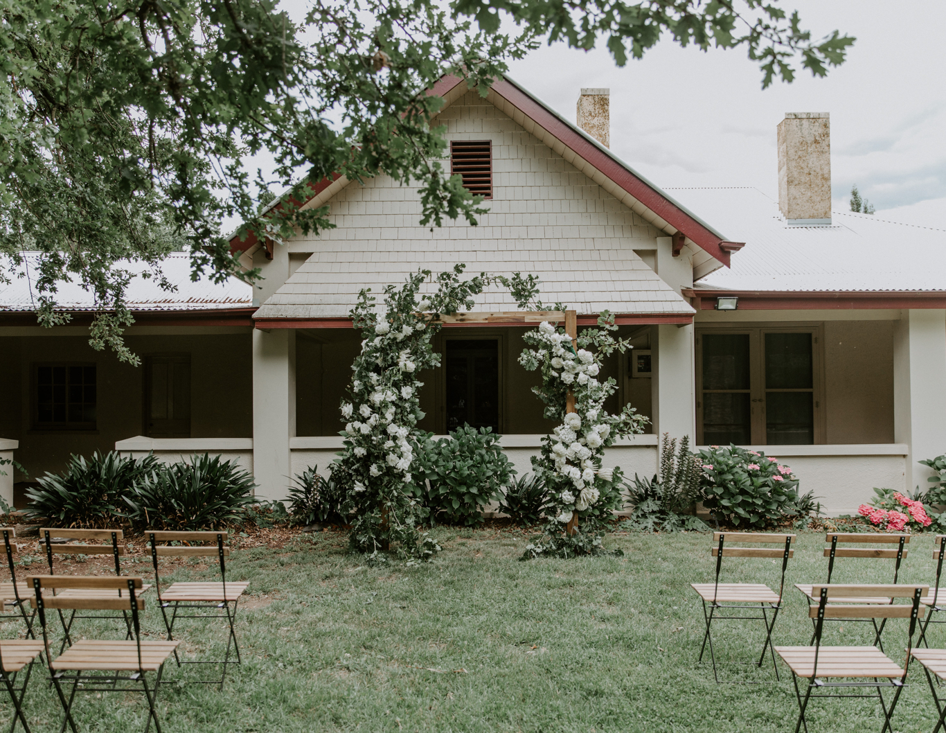 Wedding ceremony setup in front of a homestead and floral archway.