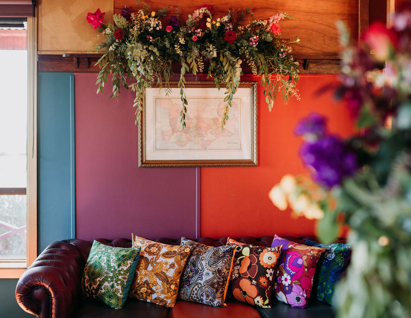 Inside colourful farm house interior with couch and decorative florals.