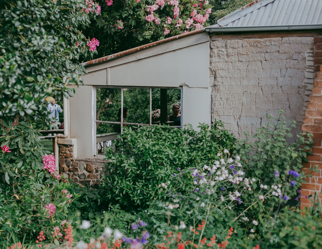 Cottage set amongst greenery and flowering plants.