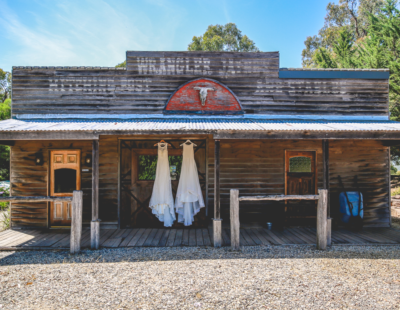 Wedding dresses hanging on the veranda of a rustic stable.