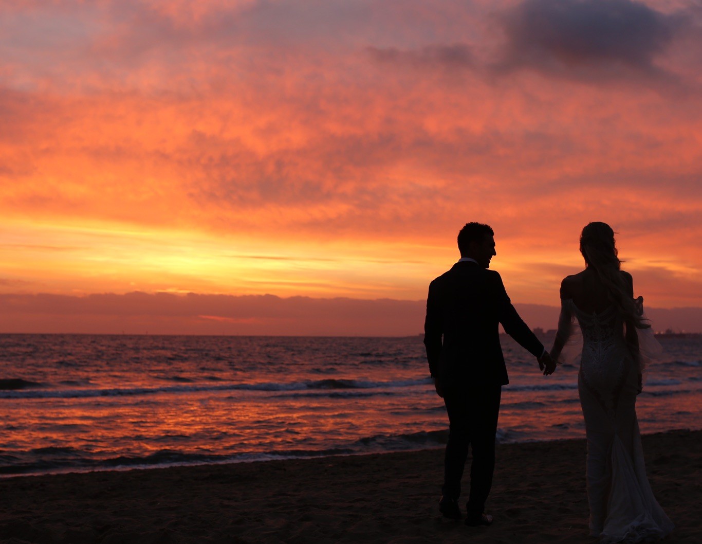 Silhouette of wedding couple at the ocean's edge.