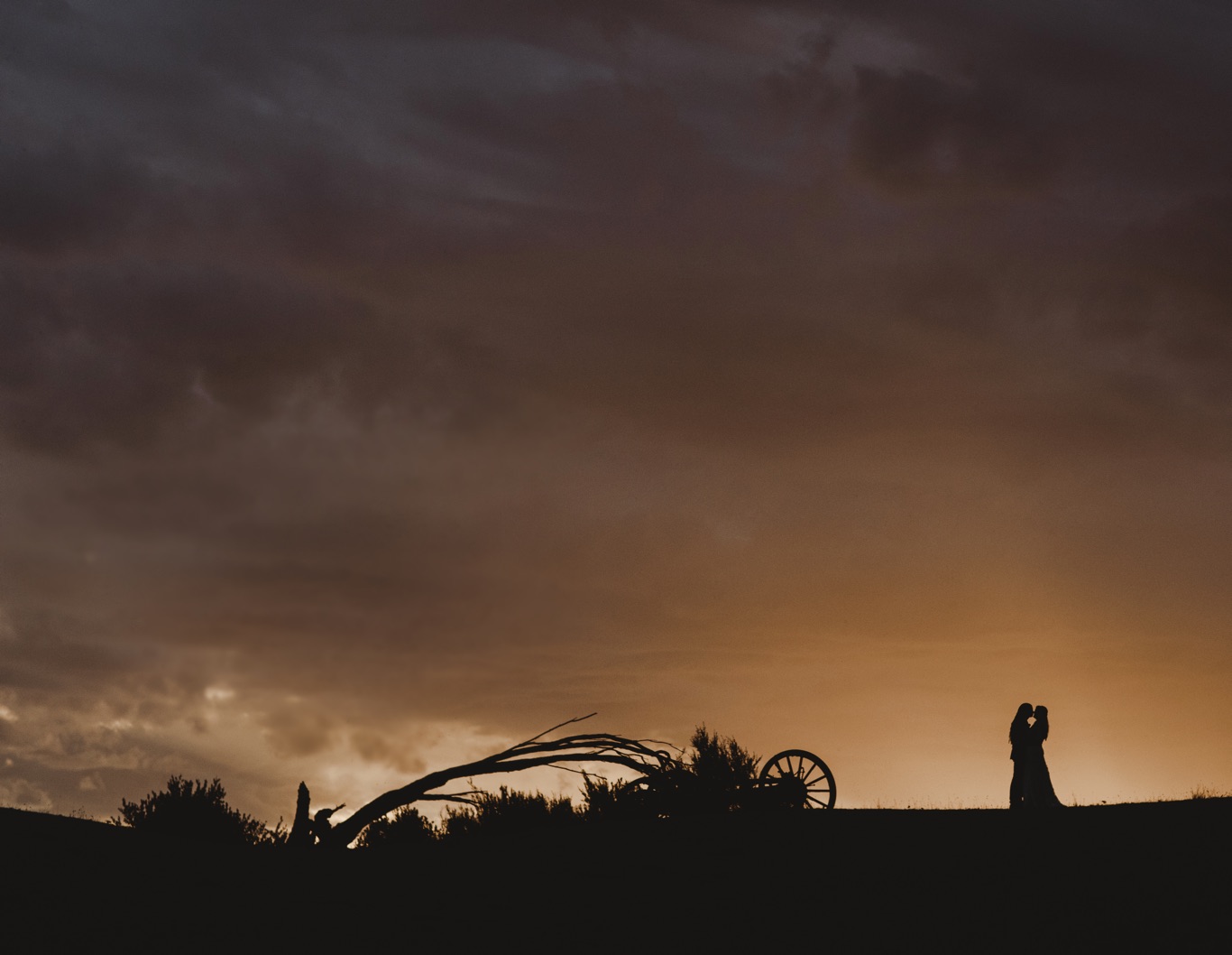 Silhouette of wedding couple and a wagon wheel.