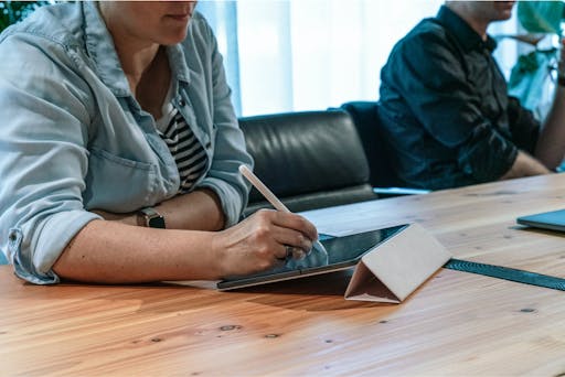 Photo of a woman working on a tablet during a meeting