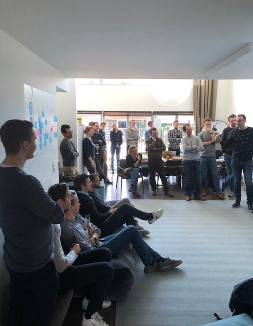 A photo of people in group circled around a wall of sticky notes during workshop session