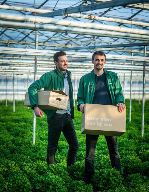 Photo of two men standing in a greenhouse holding Lokkal cardboard boxes
