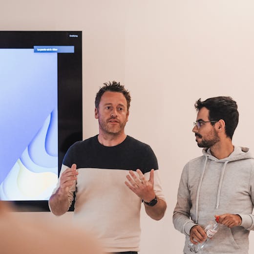 Two men standing in front of a tv presenting and explaining