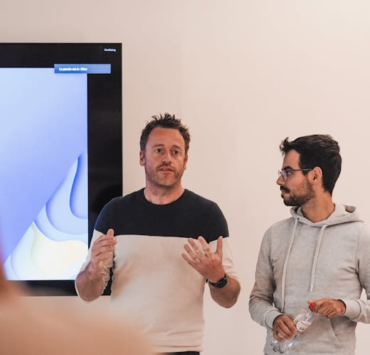 Two men standing in front of a tv presenting and explaining