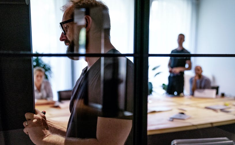 people watching a man explaining shot through a glass wall