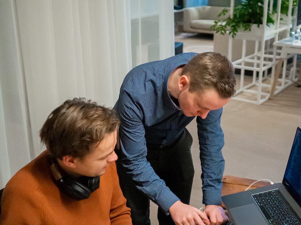 Two men behind a desk looking at a smartphone together