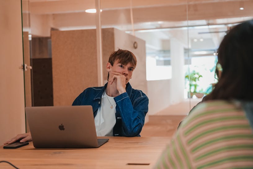 Craftzing colleague Tommy sitting in a meeting room and looking at a woman sitting in front of him
