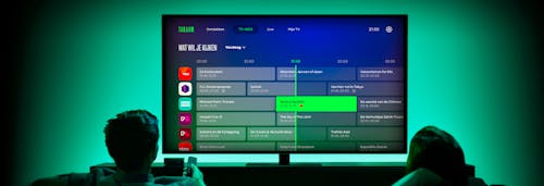 Two people watching a tv showing the Tadaam interface