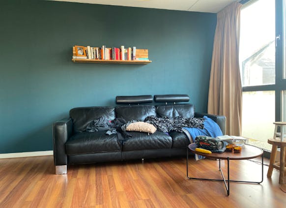 Interior with a book shelf, black leather sofa and a glass coffee table