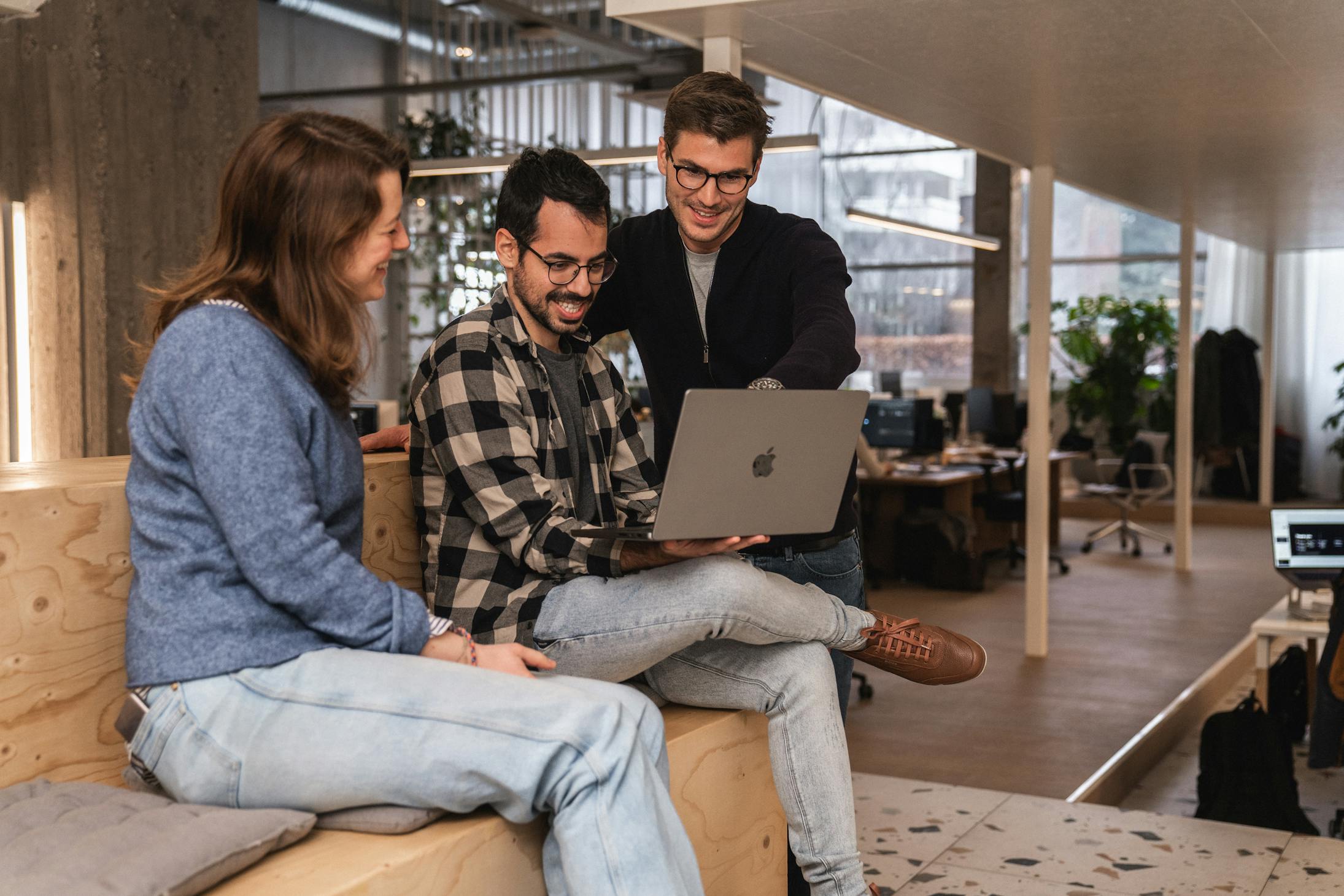Three Craftzing colleagues together looking at a laptop screen and laughing