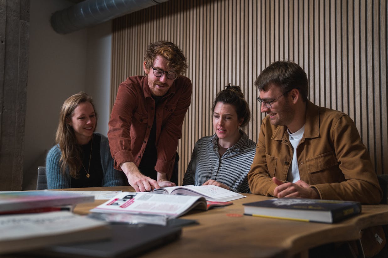Craftzing's data-team sitting in a meeting looking at a book
