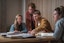 2 men and 2 women sitting at a desk going through books on the table.